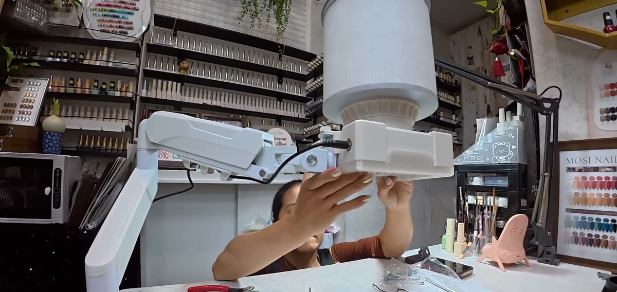 The assembled dust collector on Xiao Cui's nail desk, filter tower on top and an arm reaching over the work area